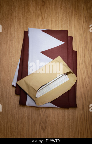 Qatar flag with a brown envelope full of money Stock Photo