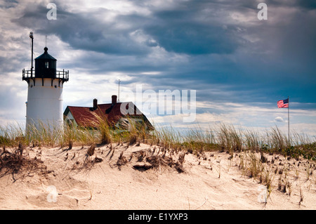 Summer storm clouds approach Race Point lighthouse as American flag waves nearby on Cape Cod, in Massachusetts. Stock Photo