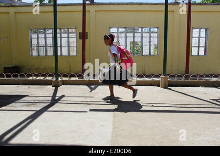 Tacloban City, Philippines. 11th June, 2014. A girl walks past a damaged school building in San Jose Central School, Tacloban City. On November 8, 2013, Haiyan, one of the most powerful typhoon to ever hit land, ravaged Eastern Visayas leaving thousands dead and homeless. Government estimates 16 million people to have been affected by the typhoon, with 6,300 reported dead and thousands more missing. Credit:  PACIFIC PRESS/Alamy Live News Stock Photo