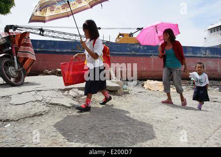 Tacloban City, Philippines. 11th June, 2014. Students walk past a giant ship which continues to lie within the community of Anibong in Tacloban City. On November 8, 2013, Haiyan, one of the most powerful typhoon to ever hit land, ravaged Eastern Visayas leaving thousands dead and homeless. Government estimates 16 million people to have been affected by the typhoon, with 6,300 reported dead and thousands more missing. Credit:  PACIFIC PRESS/Alamy Live News Stock Photo