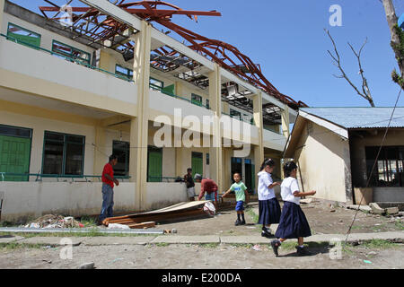 Tacloban City, Philippines. 11th June, 2014. Students walk past a damaged school building in San Jose Central School, Tacloban City. On November 8, 2013, Haiyan, one of the most powerful typhoon to ever hit land, ravaged Eastern Visayas leaving thousands dead and homeless. Government estimates 16 million people to have been affected by the typhoon, with 6,300 reported dead and thousands more missing. Credit:  PACIFIC PRESS/Alamy Live News Stock Photo