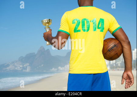 Champion Brazilian winner soccer player holding trophy and vintage football in 2014 shirt Ipanema Beach Rio de Janeiro Brazil Stock Photo