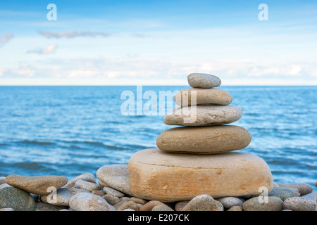 Stacked stone cairn pyramid standing on grassy hill slope beside green ...