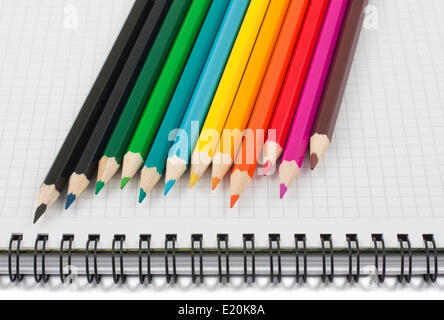 Multicolored pencils on spiral notebook Stock Photo
