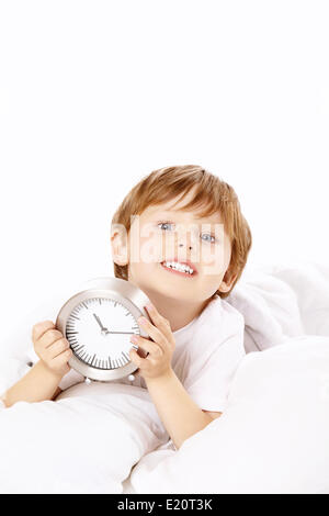 Little boy with an alarm clock in the bed Stock Photo
