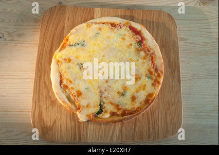 Pizza served on a wooden platter. Margherita with tomato mozzarella cheese and basil. Stock Photo