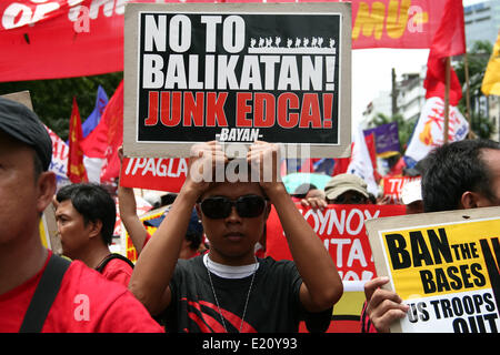 Manila, Philippines. 12th June, 2014. A protester holding a poster against the Enhanced Defense Cooperation Agreement. Several hundred protesters held different protest rallies all over Metro Manila marking the Philippines' 116th Independence Day. Different groups called for accountability and transparency regarding the corruption scandals of high ranking government officials. The protesters also called for the ouster of President Aquino for his alleged incompetency in governing his administration. Credit:  PACIFIC PRESS/Alamy Live News Stock Photo