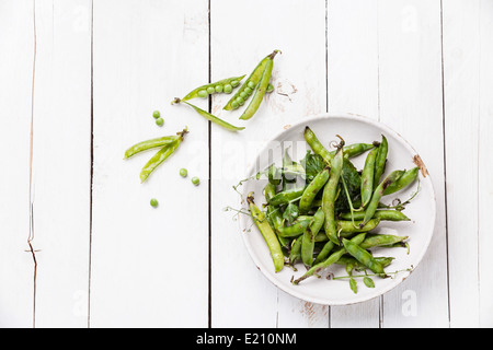 Fresh green pea in pods on white wooden background Stock Photo