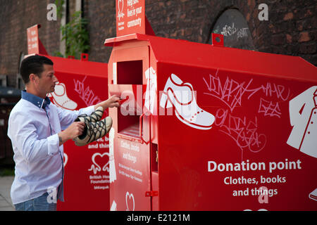 Man (MR) at donation point, clothing charity clothes donate giving charitable used container give secondhand poor need support welfare collection give donated Stock Photo