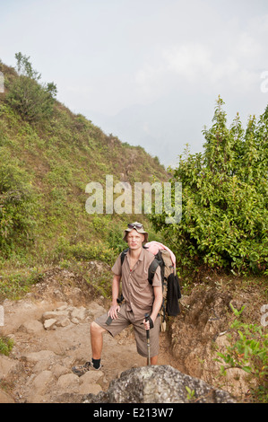 Male tourist climbing Himalayan mountain range in Nepal Stock Photo
