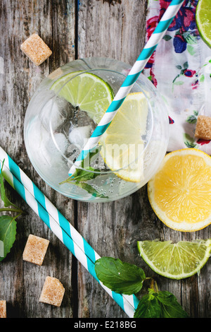 Fresh homemade lemonade with lemon, lime and mint in glasses with vintage cocktail tube over wooden table. Top view. Stock Photo