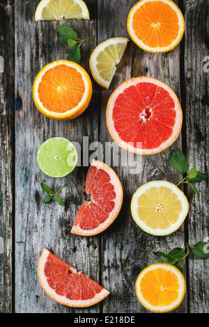 Set of sliced citrus fruits lemon, lime, orange, grapefruit with mint over wooden background. Top view. Stock Photo