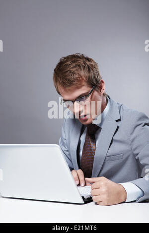 A young man in a suit looking at laptop Stock Photo