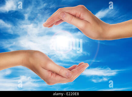 female hands over blue sky with clouds Stock Photo