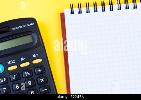 Notepad and calculator on yellow background. Stock Photo