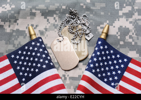 Closeup of two crossed American Flags on camouflage material with dog tags in the middle. Stock Photo