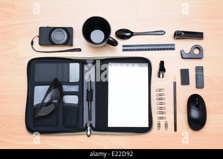 High angle shot of all black assorted desk items. Items include: mug, stapler, pencil, pen, eraser, paper clips, notebook Stock Photo