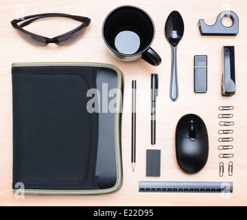 High angle shot of all black assorted desk items. Items include: mug, stapler, pencil, pen, eraser, paper clips, notebook Stock Photo