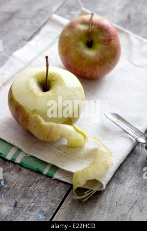 Peeled Apple on old wooden background, backlit Stock Photo