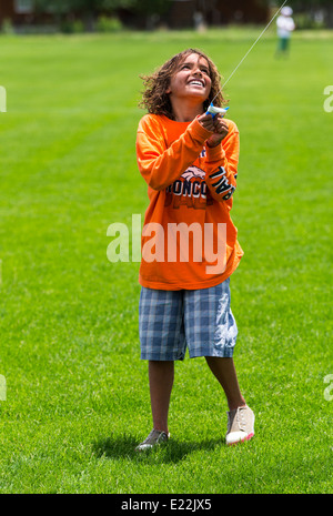 Young boy flying a kite on a grassy field Stock Photo