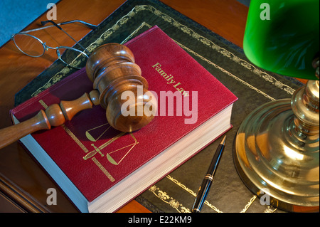 LAW COURT CHAMBERS JUDGE SENTENCING DELIBERATIONS wooden gavel on 'Family Law' book with scales of justice emblem lit by desk lamp on traditional desk Stock Photo