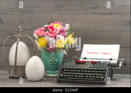 Easter still life with tulips, eggs and antique typewriter. Sample text Happy Easter in french language Stock Photo