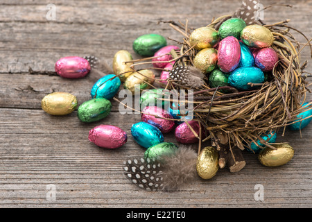 multicolor chocolate easter eggs in nest on wooden background Stock Photo