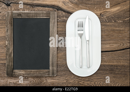 blackboard for menu on wooden table with white plate and silverware. space for your text and recipes Stock Photo