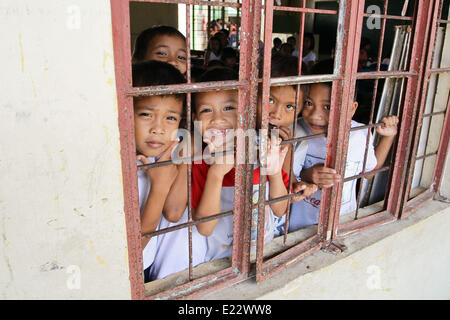 Tacloban, Philippines. 11th June, 2014. Students pose for a picture in San Jose Central School, Tacloban City on June 11, 2014. On November 8, 2013, Haiyan, one of the most powerful typhoon to ever hit land, ravaged Eastern Visayas leaving thousands dead and homeless. Government estimates 16 million people to have been affected by the typhoon, with 6,300 reported dead and thousands more missing. Housing and livelihood are among the serious challenges in the rehabilitation process in Haiyan-affected areas seven months after the disaster. © Mark Cristino/NurPhoto/ZUMAPRESS.com/Alamy Live News Stock Photo