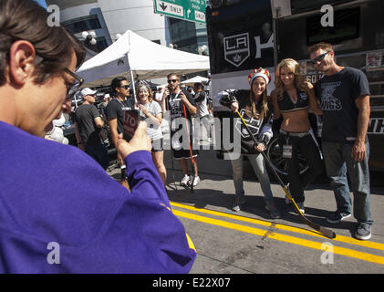 Los Angeles, California, USA. 13th June, 2014. The Los Angeles Kings defeated the New York Rangers in double overtime in game 5 of the Stanley Cup National Hockey League Finals at Staples Center in Los Angeles on Friday evening, June 13, 2014. Several thousand fans spilled out into the streets surrounding Staples center in downtown Los Angeles to celebrate the win. LA Kings fans take a photo with an LA Kings girl on Friday afternoon before the game. Credit:  David Bro/ZUMAPRESS.com/Alamy Live News Stock Photo