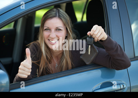 A happy driver leaning out of the window and showing the car key Stock Photo