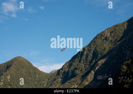New Zealand, South Island, Fiordland National Park, Milford Sound aka Piopiotahi. Flightseeing helicopter flying over the fjord. Stock Photo
