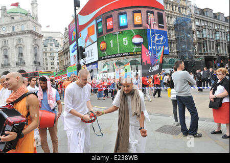 Piccadilly Circus, London, UK. 14th June 2014. A group of Hare Krishna devotees at Eros in Piccadilly Circus just at the same moment as the Jesus Army passes along towards Trafalgar Square. Credit:  Matthew Chattle/Alamy Live News Stock Photo