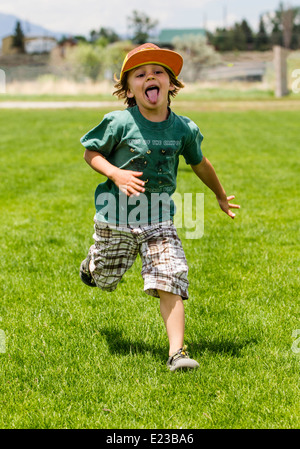 Young boy running on a grassy park field Stock Photo