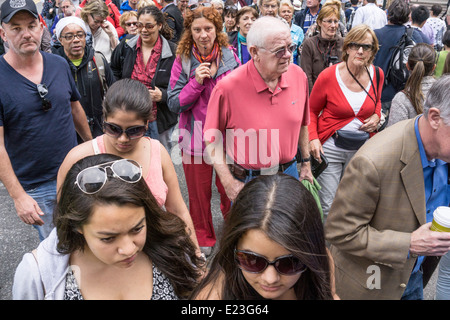 thoughtful faces in crowd crossing Trinity Place on direct approach to partially completed World Trade Center memorial plaza Stock Photo