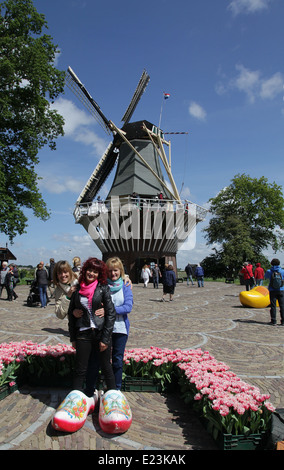 A windmill at the Keukenhof in the Netherlands.tourists in clogs posing for camera.wooden shoes. Stock Photo
