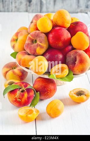 Ripe apricots, nectarines and saturn peaches on ceramic holder. Selective focus. Stock Photo