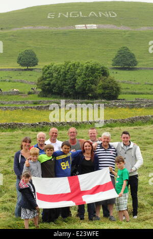 Peak District, Derbyshire, UK.  15 June 2014.  Members of a group of 15 villagers who have created a   sign in on a hillside above Chelmorton village near Buxton.  Local resident Phil Swindell, 44, remains optimistic about England’s chances despite their defeat against Italy.  The builder said: “I think we did alright but it makes it very hard.  We’ll be alright.  Optimists aren’t we.” Credit:  Matthew Taylor/Alamy Live News Stock Photo