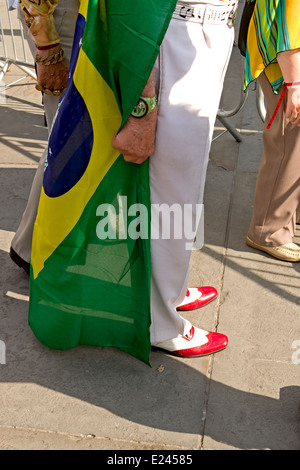 A man in snazzy shoes with a Brazilian flag draped round him at the Brazil Day celebrations in Trafalgar Square. Stock Photo