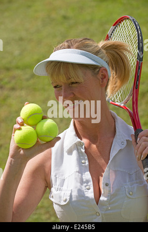 Female tennis player holding racquet and three balls in her hand Stock Photo