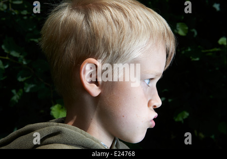 Headshot, side view Portrait Angry Child  isolated dark background. Negative Human face Expressions, Emotions, Conflict, Grimace Stock Photo