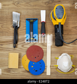 Overhead view of sanding and painting equipment positioned on rustic wooden boards. Stock Photo