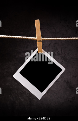 Photography paper with instant photo frame attached to rope with clothes pins. Copy space for your image. Stock Photo