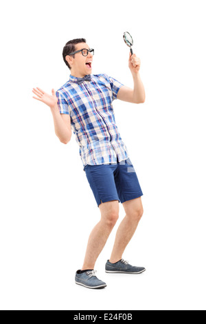 Full length portrait of an excited man looking through magnifier Stock Photo