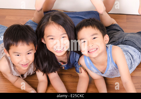 Three happy children lying on floor Stock Photo