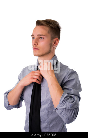 Elegant young man wearing and adjusting neck-tie, isolated on white Stock Photo