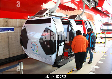 La Paz, Bolivia. 16th June, 2014. A woman boards a gondala in the form of a football in the terminal in El Alto, on the new cable car / gondola lift system linking El Alto to La Paz. Several gondolas have been changed to a football design to celebrate the 2014 World Cup currently being held in Brazil. The first of three cable car lines was inaugurated on 30th May 2014, in total they will form the longest and highest urban cable car system in the world. Credit:  James Brunker/Alamy Live News Stock Photo