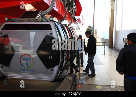 La Paz, Bolivia. 16th June, 2014. People board a gondola in the form of a football in the terminal in El Alto, on the new cable car / gondola lift system linking El Alto to La Paz. Several gondolas have been changed to a football design to celebrate the 2014 World Cup currently being held in Brazil. The first of three cable car lines was inaugurated on 30th May 2014, in total they will form the longest and highest urban cable car system in the world. Credit:  James Brunker / Alamy Live News Stock Photo