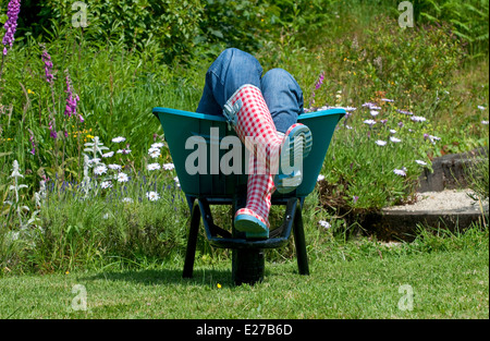 female laying in garden wheelbarrow Stock Photo