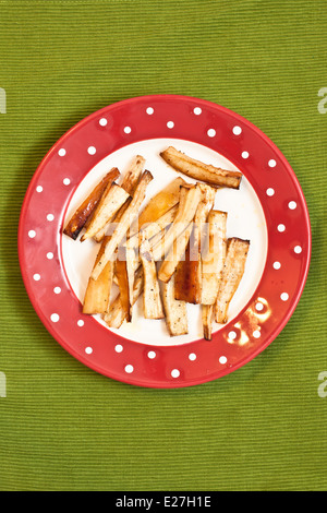 Plate of honey roasted parsnips on a table Stock Photo